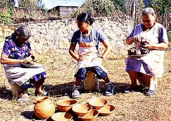 elder women and a young woman working with unfired pottery