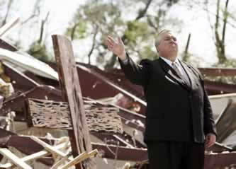 photo of a well-dressed man standing in front of wreckage