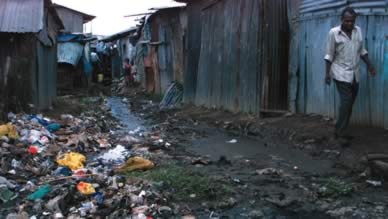 A Kenyan slum dweller avoids trash and sewage as he walks in the Nairobi slum of Kibera. -Reuters photo
